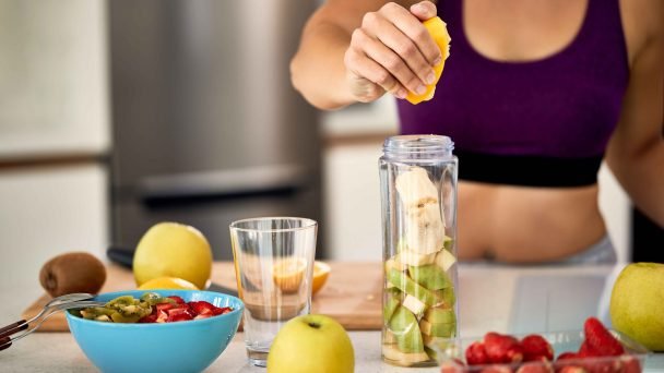 closeup-de-desportista-usando-limao-ao-fazer-smoothie-de-frutas-em-casa